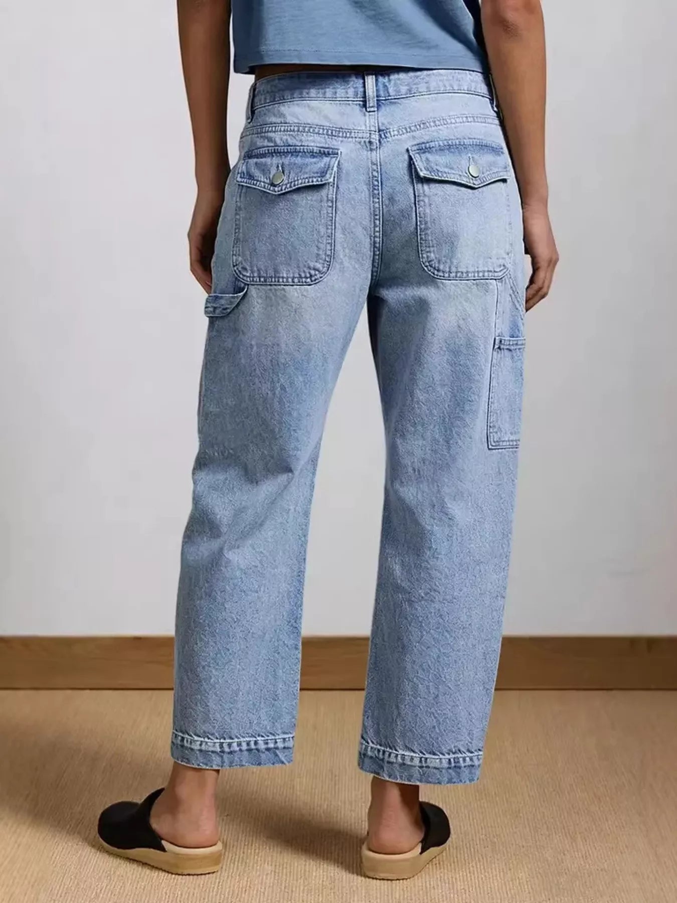 Person wearing light blue jeans on a plain background