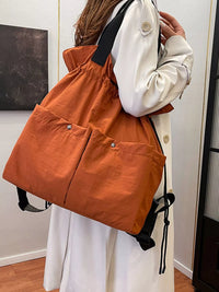 Person holding an orange drawstring bag indoors