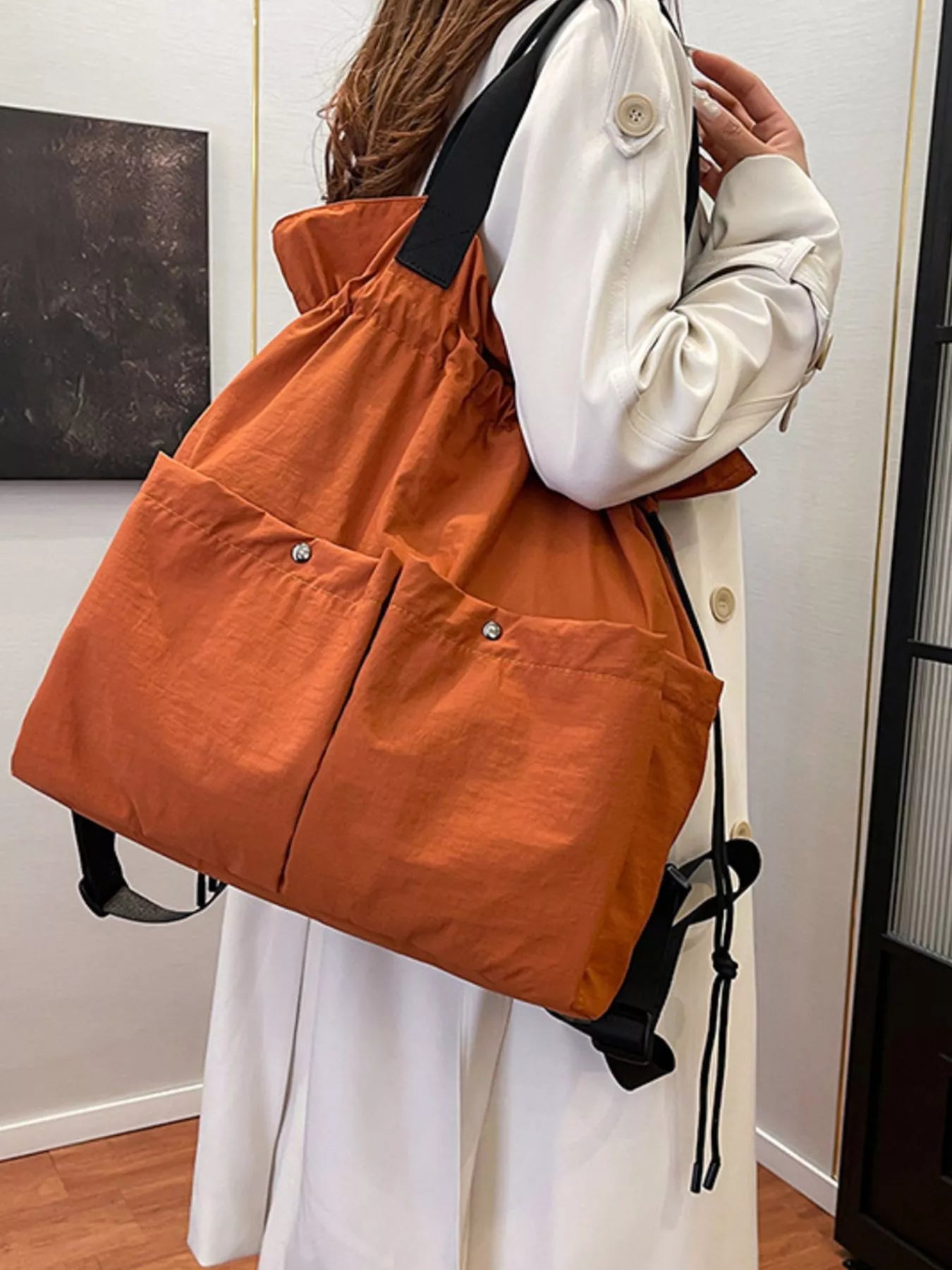 Person holding an orange drawstring bag indoors