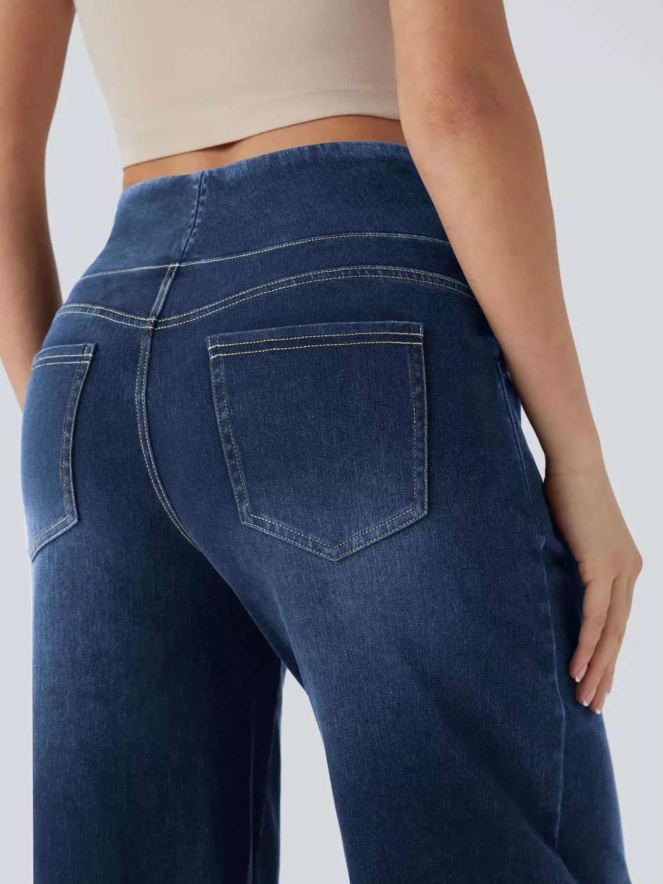 Person wearing blue jeans on a plain background