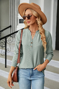 Woman wearing a green shirt, brown hat, and sunglasses outdoors.