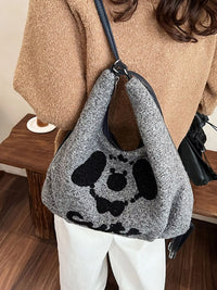 Person wearing a gray textured handbag with black paw prints and 'Gucci' logo.