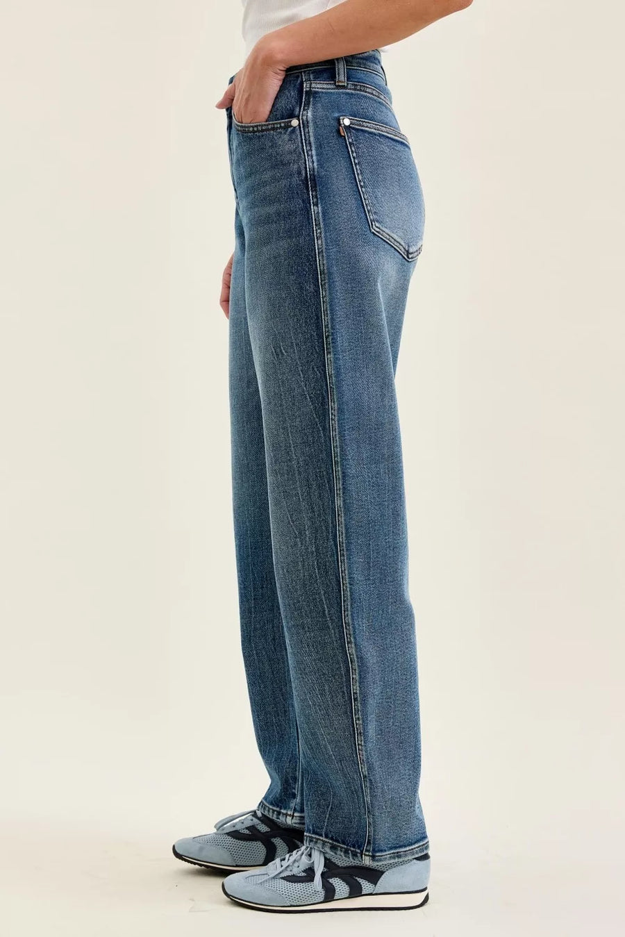 Person wearing blue jeans on a plain background