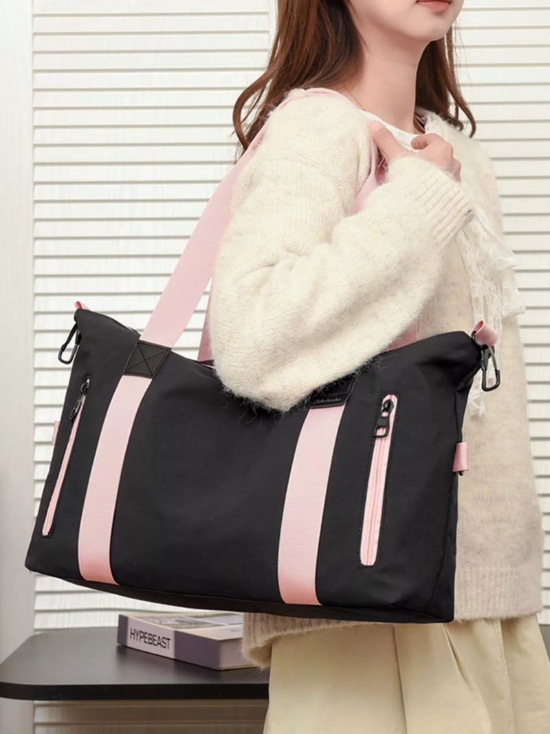 Person holding a black and pink bag with a white sweater and beige pants.