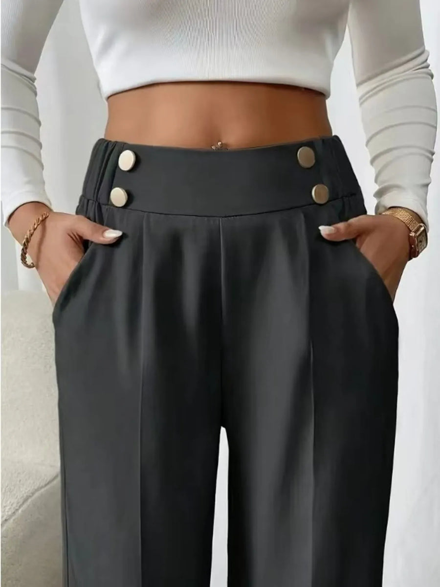 Person wearing black high-waisted pants with button details and a white cropped top.