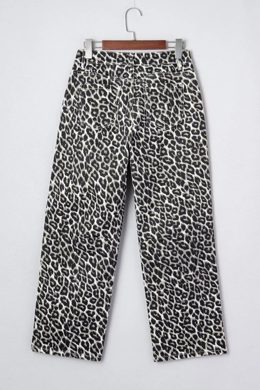 Leopard print pants on a hanger against a white background