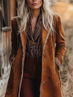 Person wearing a long brown coat with intricate patterns, standing outdoors.