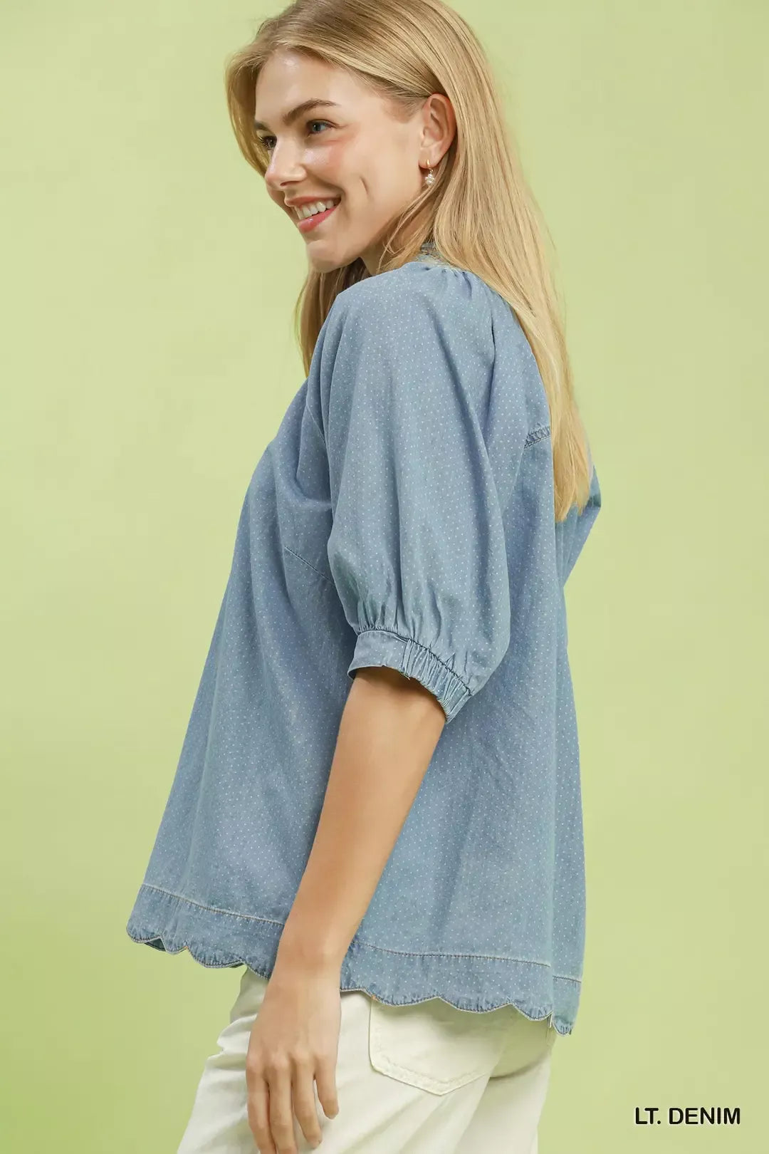 Woman wearing a light denim blouse against a light green background