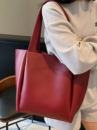 Red tote bag held by a person in an indoor setting