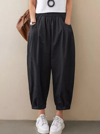 Person wearing black wide-leg pants with a plain background
