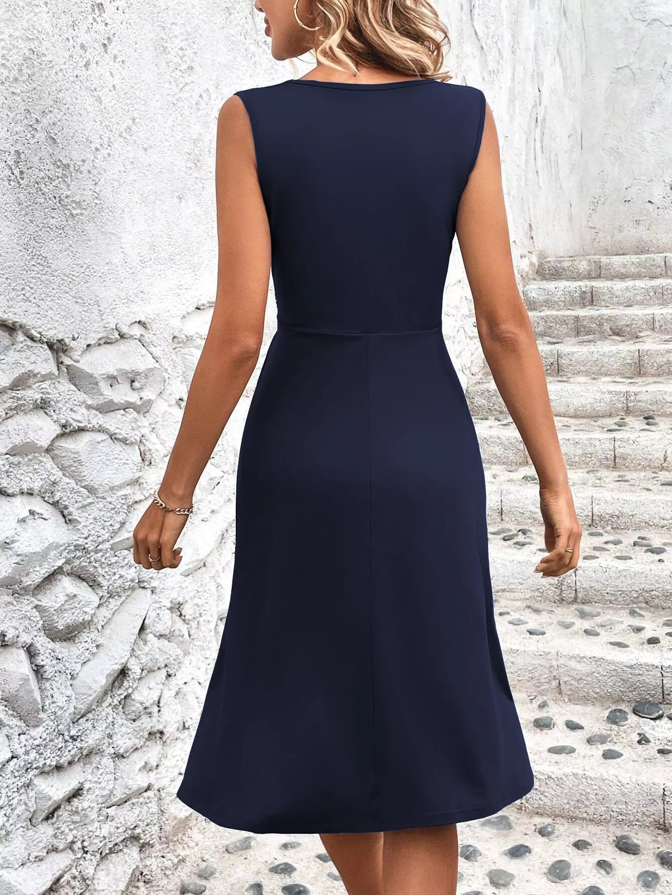 Navy blue dress worn by a person standing on stone steps with a textured wall background