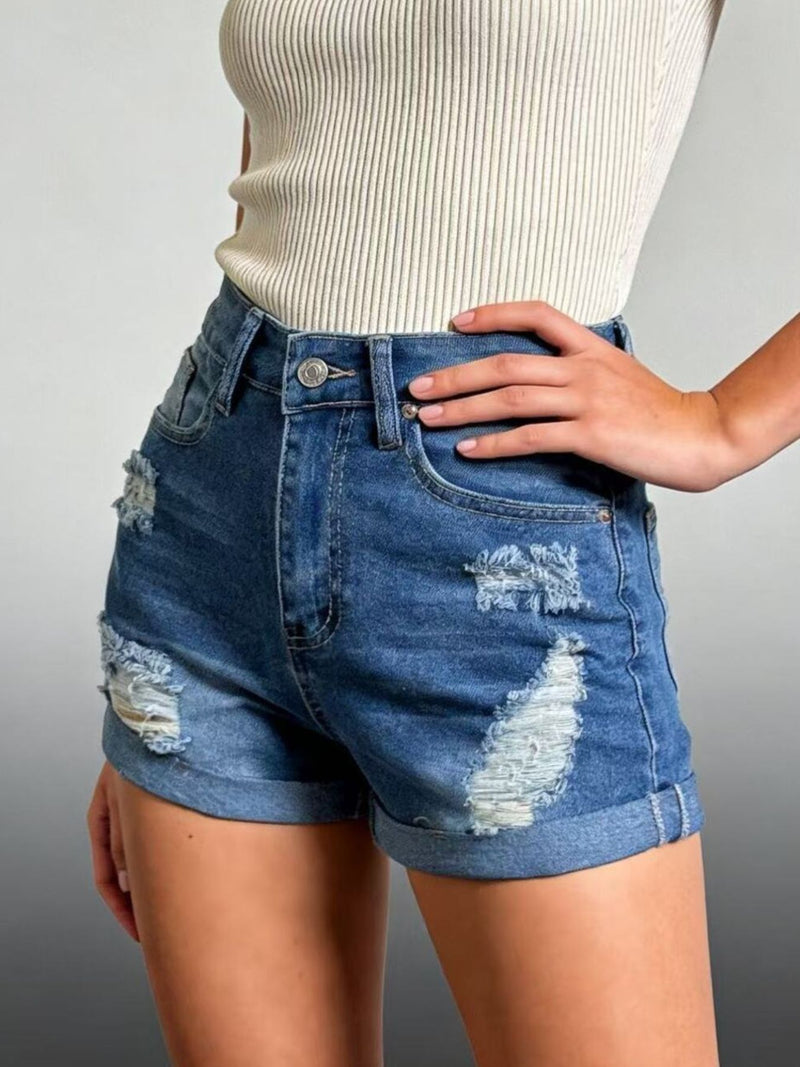 Person wearing distressed blue denim shorts on a gray background