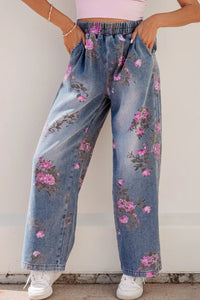 Person wearing floral jeans with a plain background