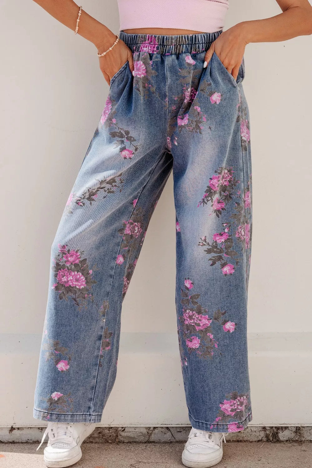 Person wearing floral jeans with a plain background