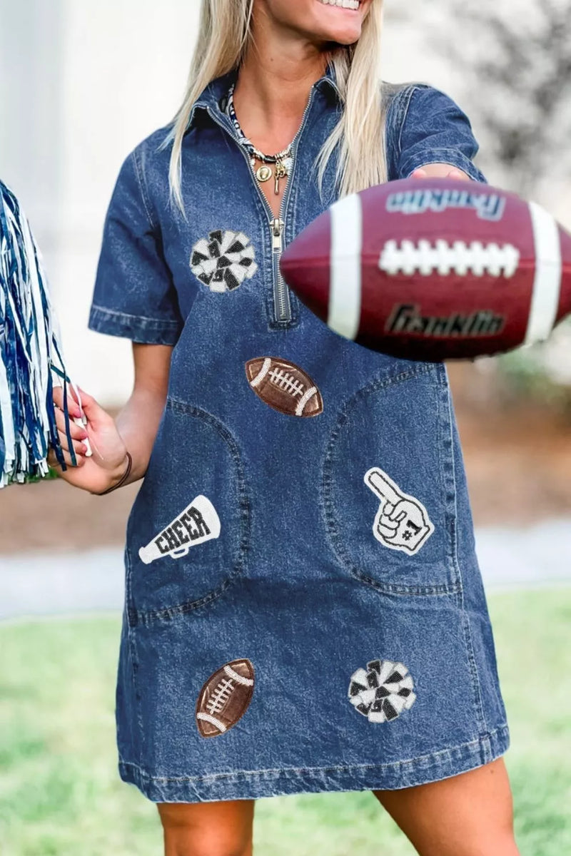 Woman wearing a denim dress with sports-themed patches holding a football.