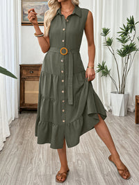 Woman wearing a green dress with a belt in a room with plants and furniture.