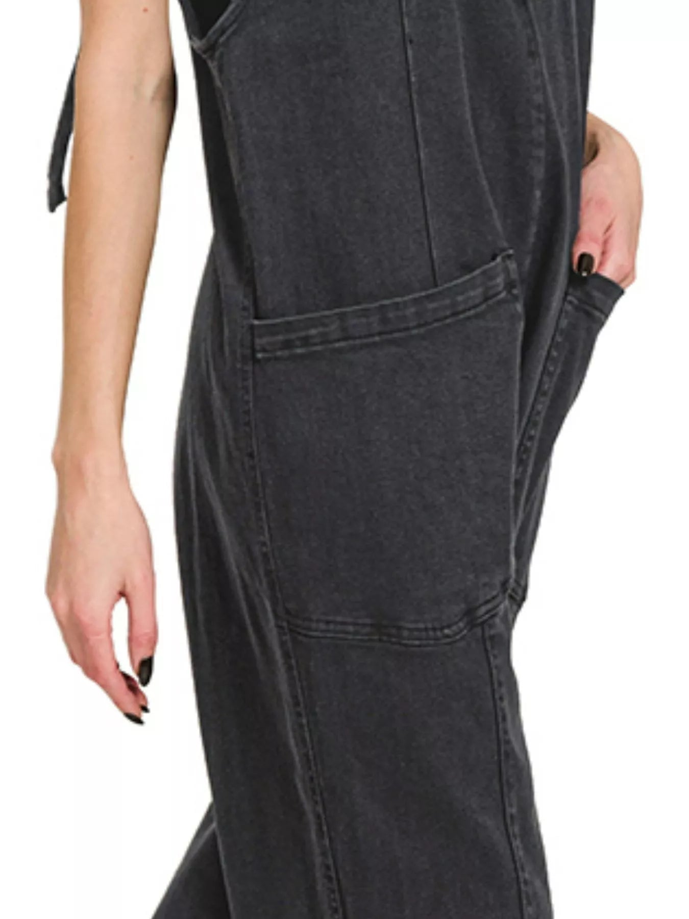 Black denim jumpsuit worn by a person on a white background