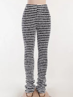 Black and white striped knit leg warmers worn on a person's legs, shown from the waist down against a plain light background.