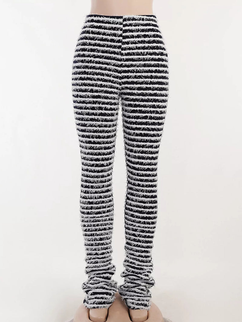 Black and white striped knit leg warmers worn on a person's legs, shown from the waist down against a plain light background.