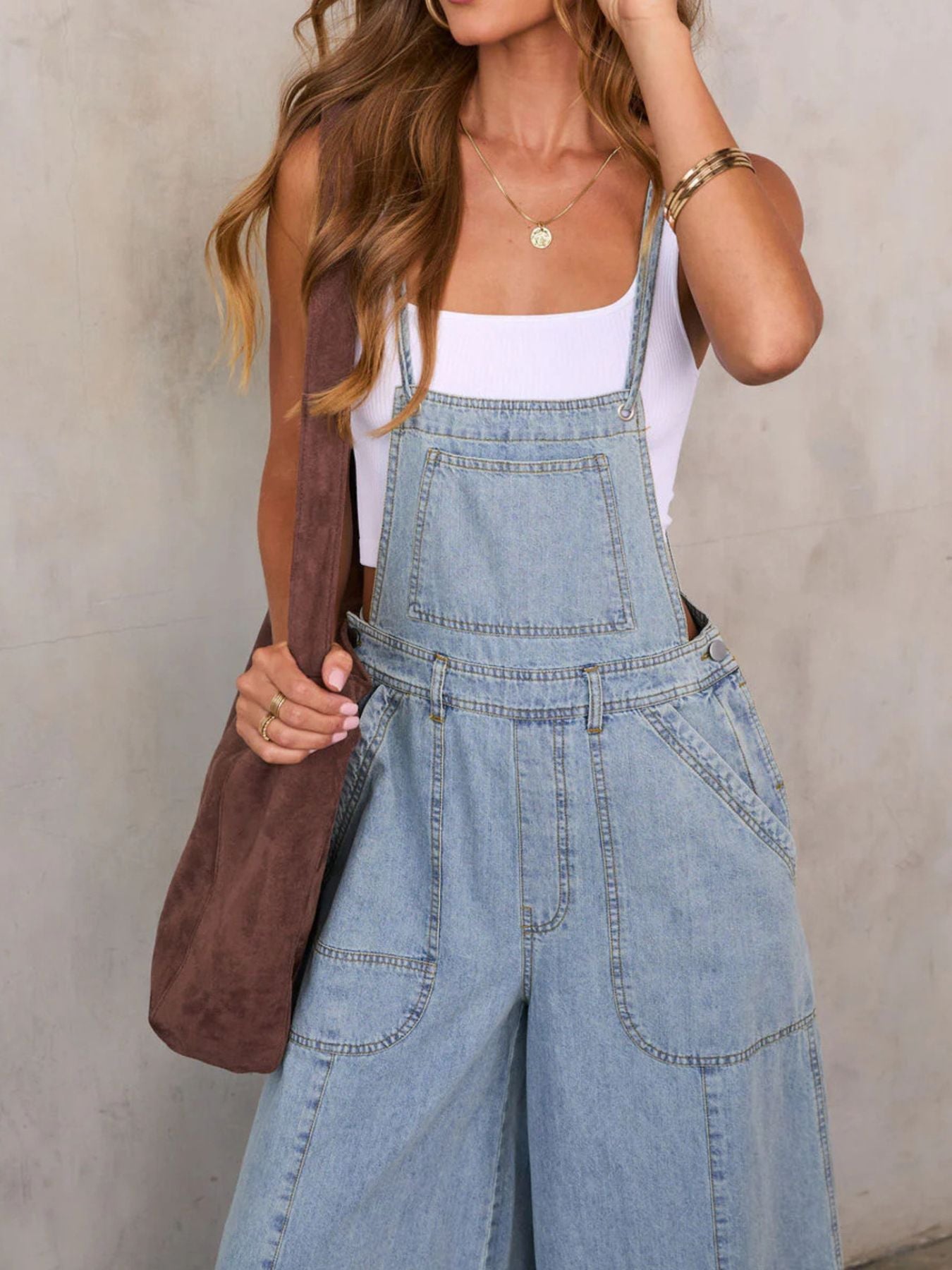 Person wearing denim overalls with a plain background