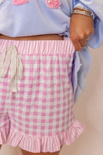 Pink checkered shorts with ruffle details worn by a person.