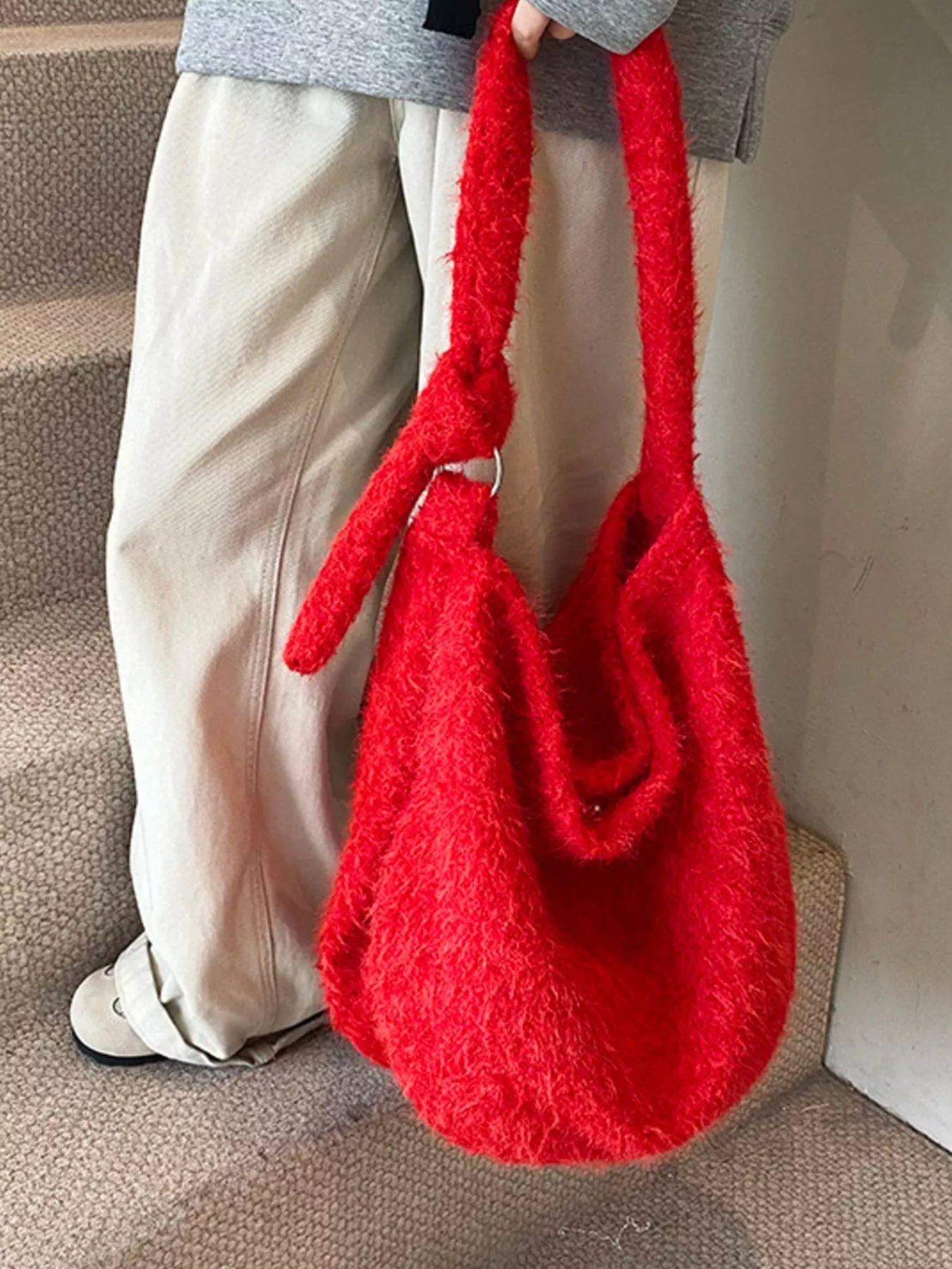 Red textured handbag held by a person on a neutral background