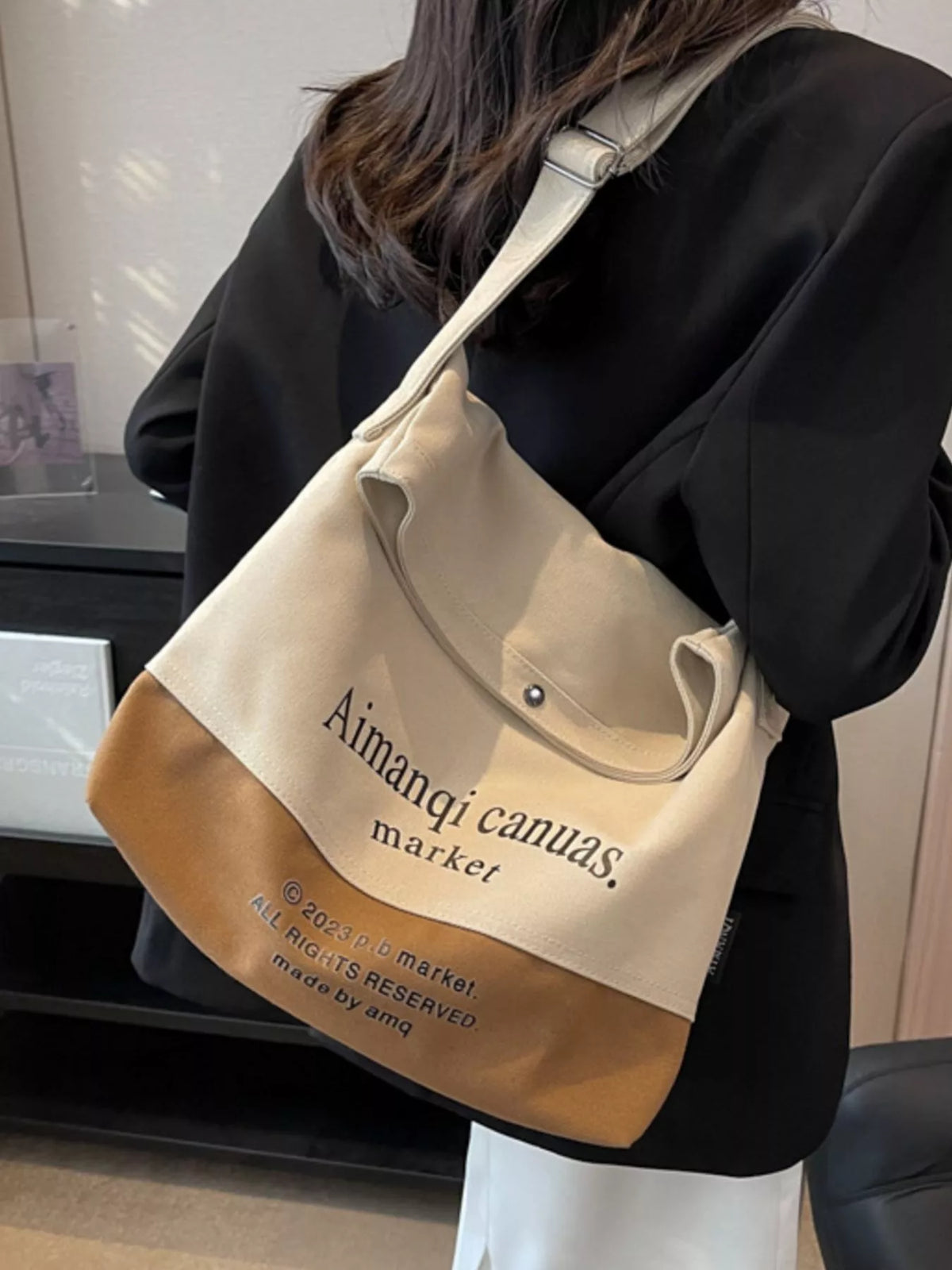 Person wearing a beige and brown tote bag with 'Aimangi canvas' branding.