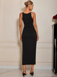 Woman wearing a black sleeveless dress against a neutral wall.