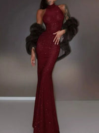 Woman wearing a burgundy evening gown with a fur stole against a neutral background