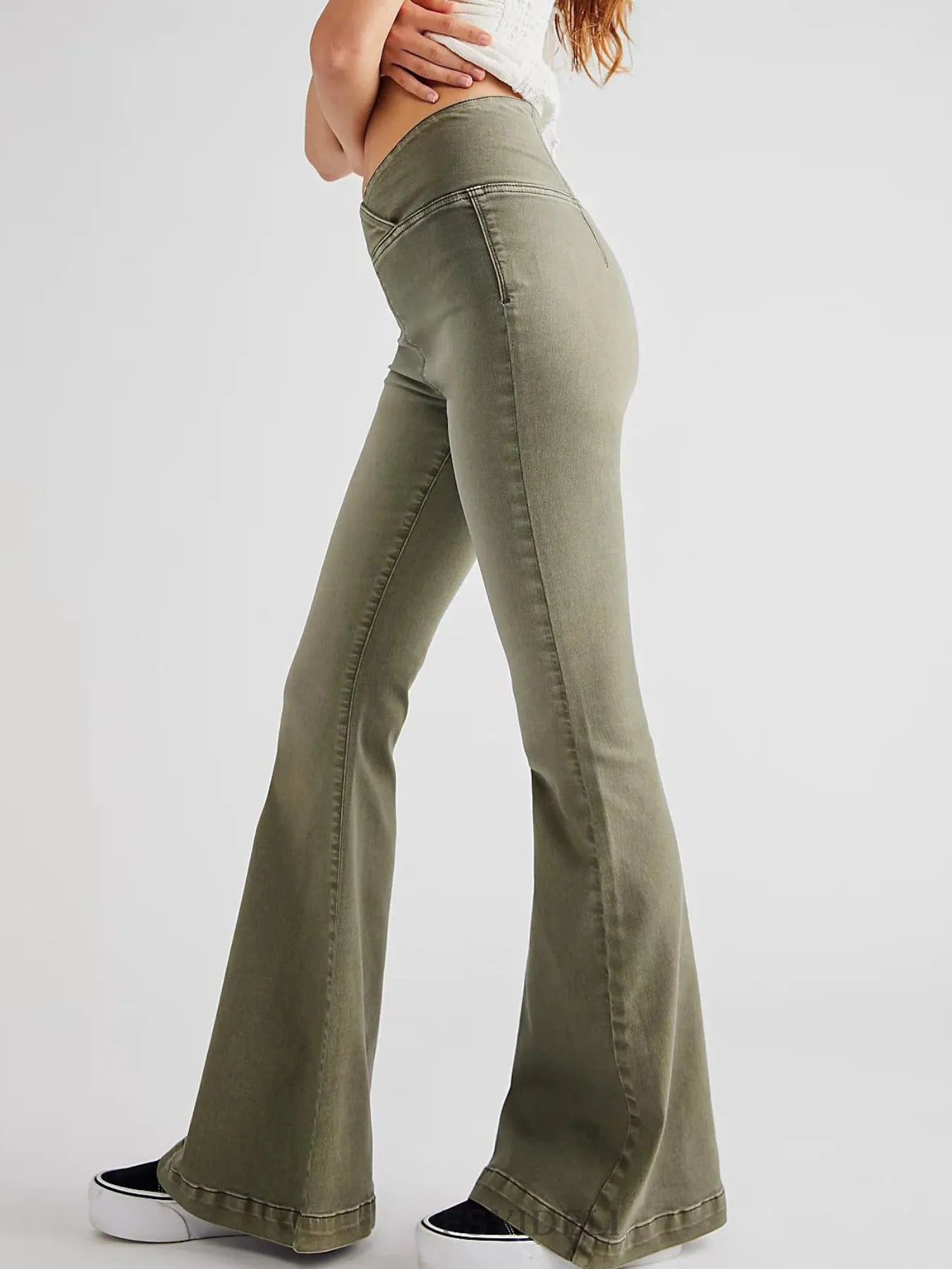Green flared jeans worn by a person on a white background