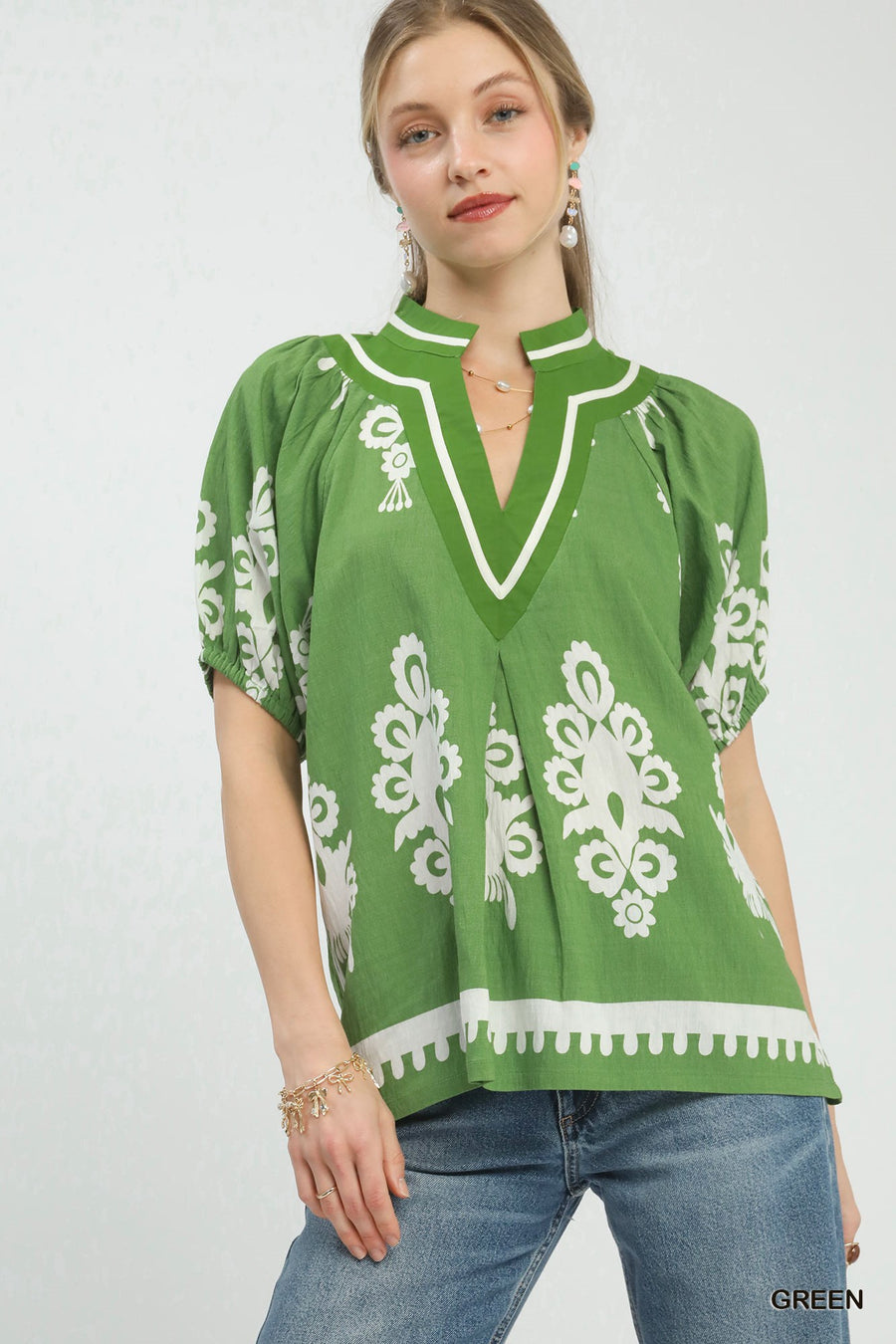 Woman wearing a green blouse with white patterns on a white background