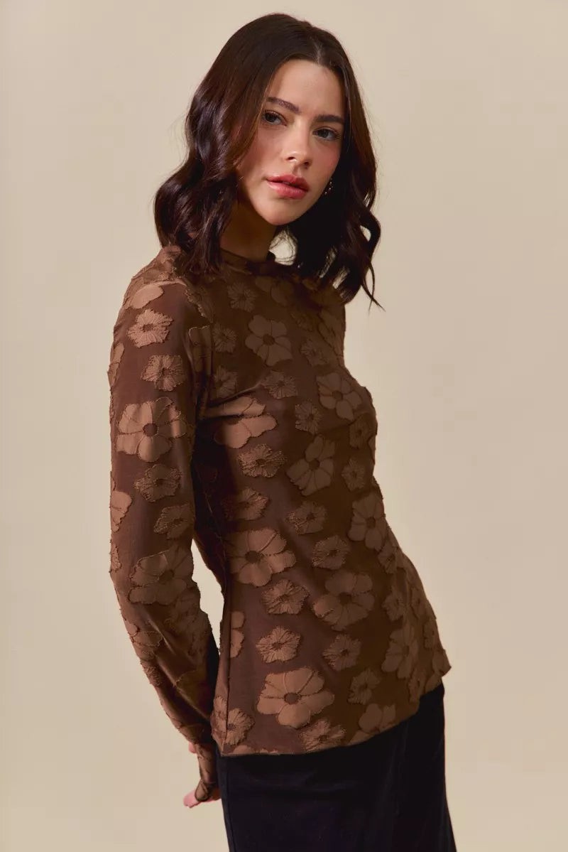 Woman wearing a brown floral patterned top against a beige background