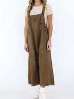 Person wearing brown denim overalls on a white background