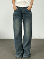Person wearing blue jeans and a white shirt against a plain background
