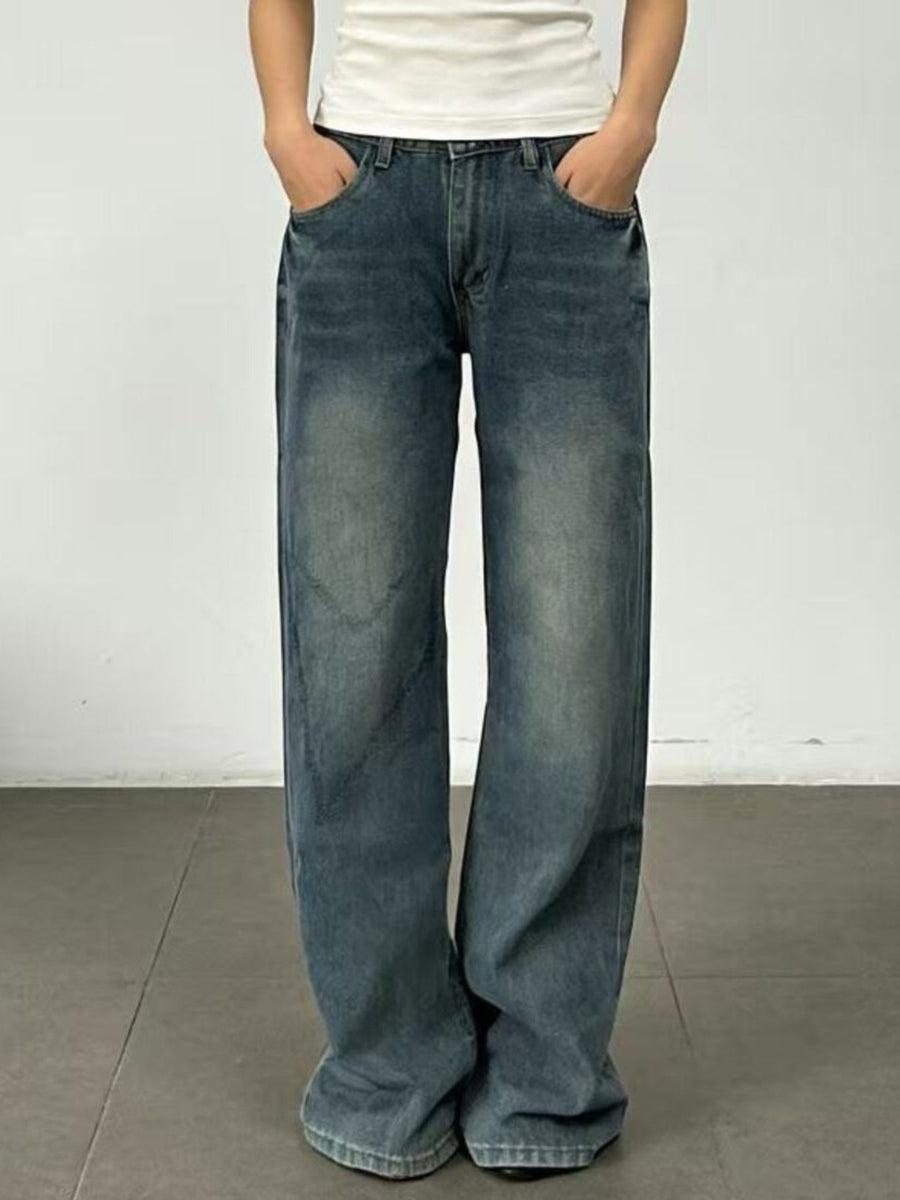 Person wearing blue jeans and a white shirt against a plain background