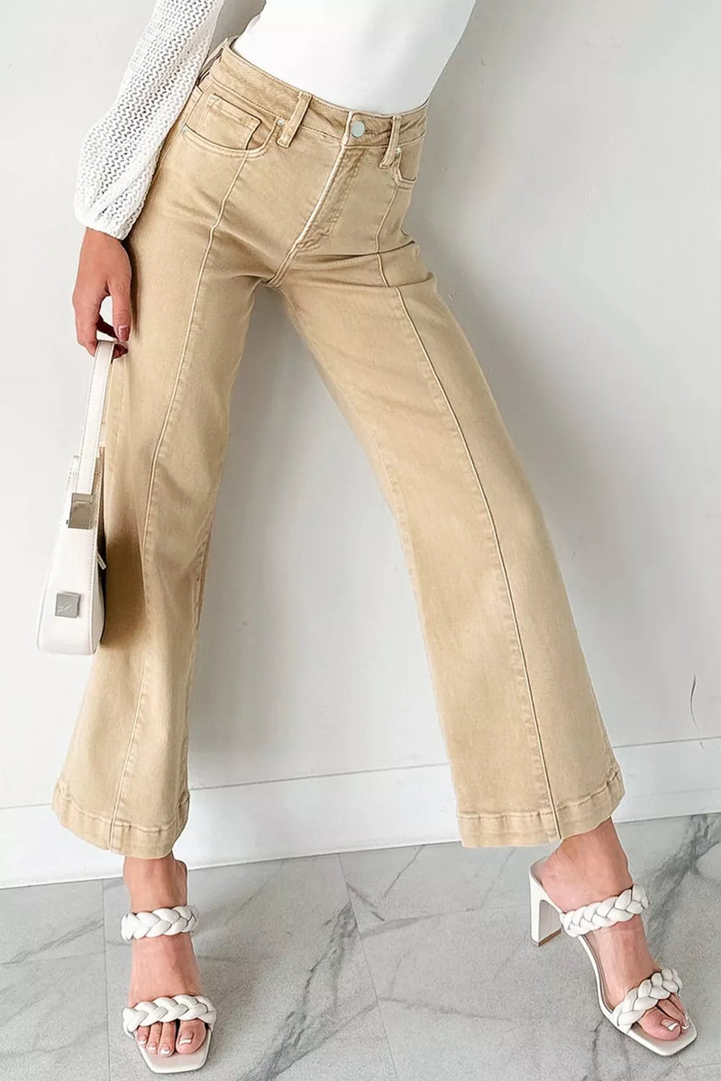 Person wearing beige pants and white sandals on a marble floor with a white wall background