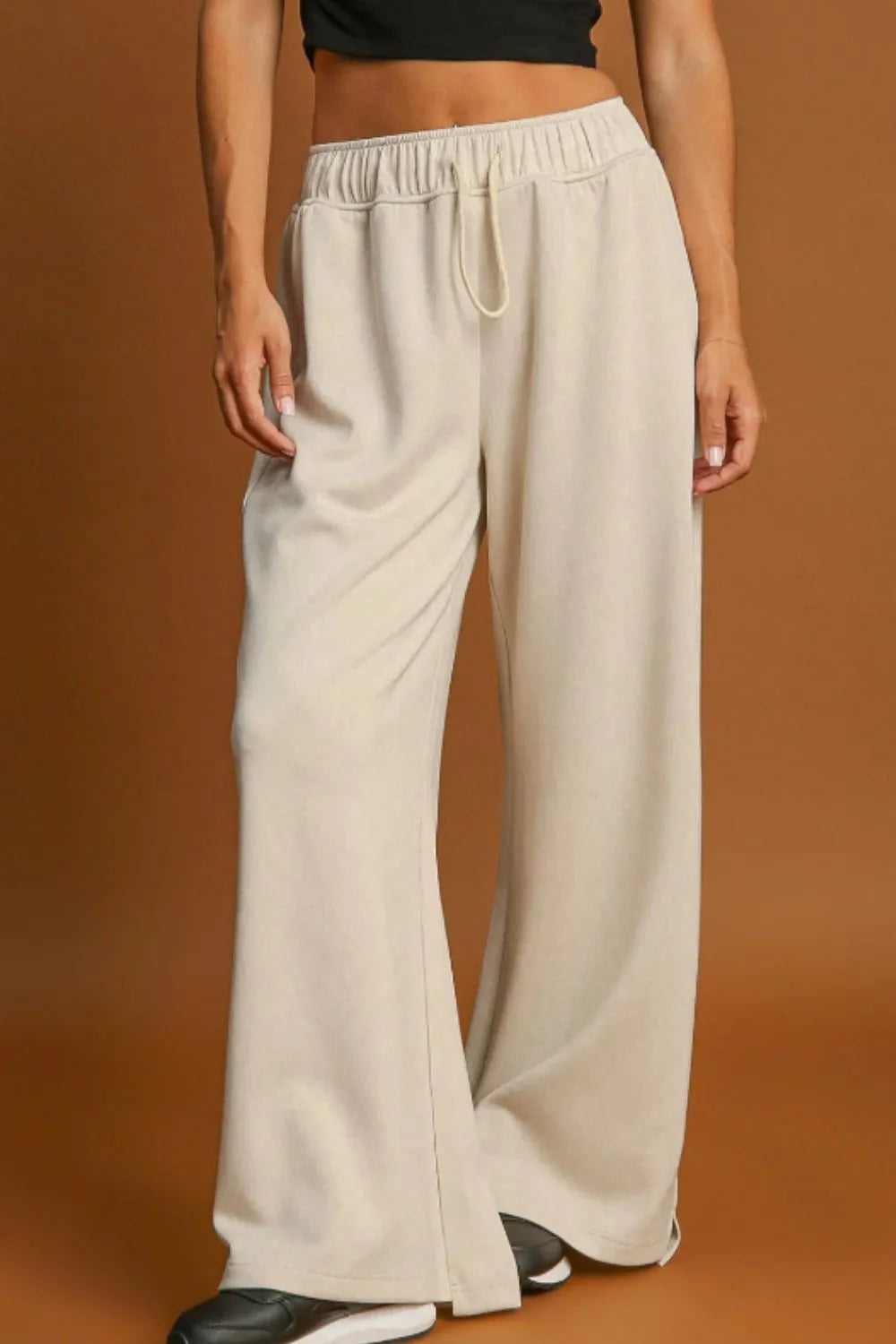 Beige wide-leg pants worn by a person on a brown background