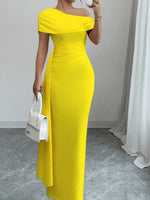 Woman wearing a yellow off-shoulder dress holding a white handbag indoors.