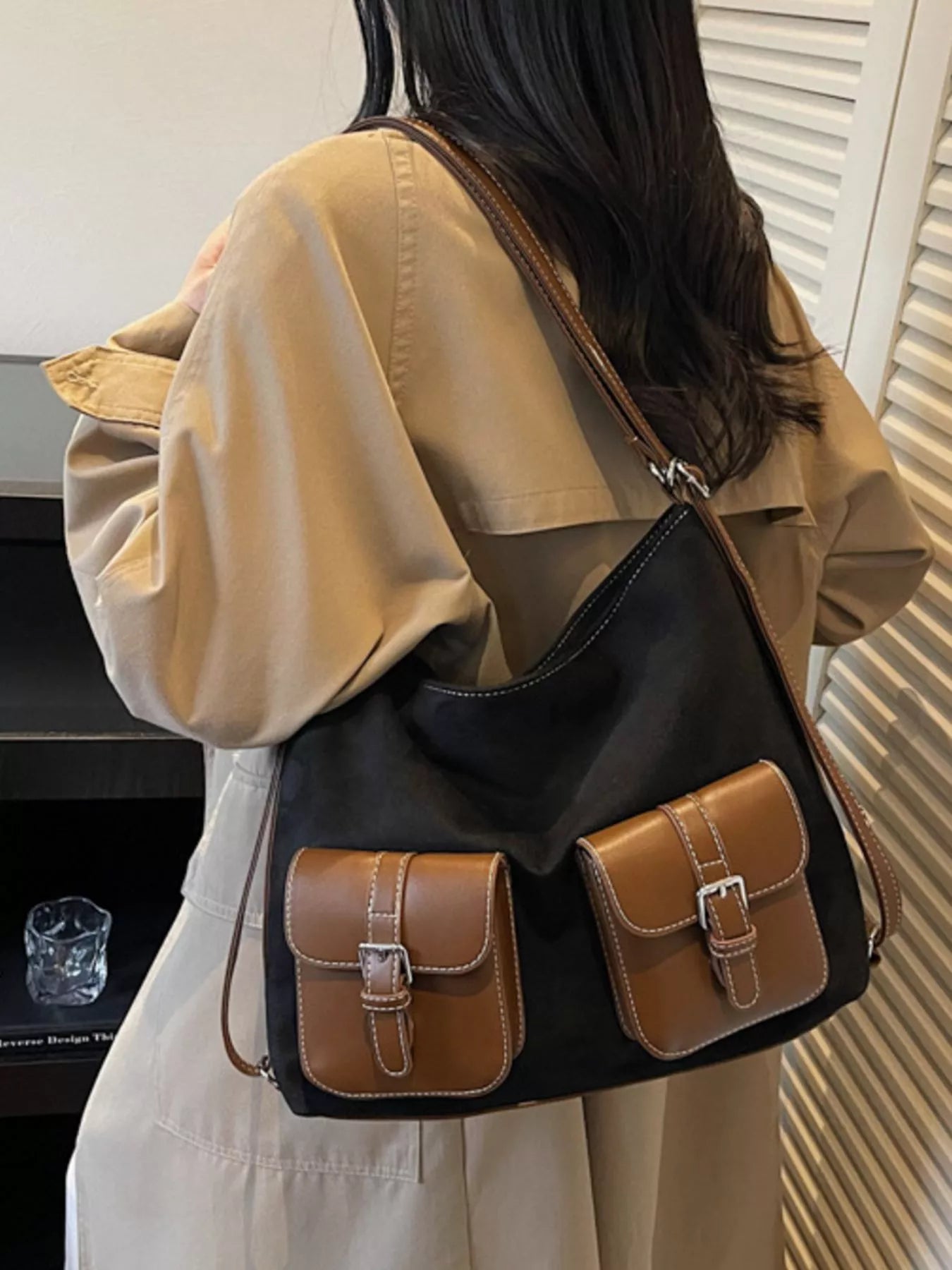 Person wearing a black and brown handbag with a neutral background