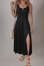 Woman wearing a black dress with a slit, standing against a plain background