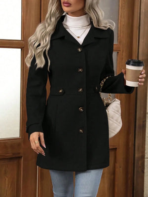 Person wearing a black coat holding a coffee cup in front of a wooden door.