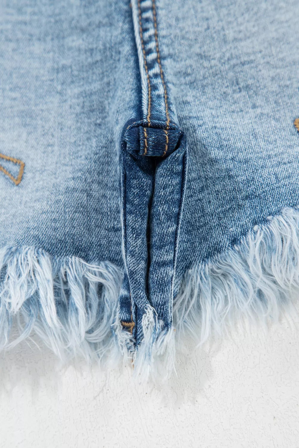 Close-up of a frayed denim edge with a white background