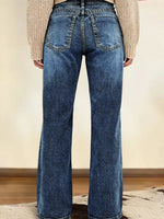 Person wearing blue flared jeans with a neutral background