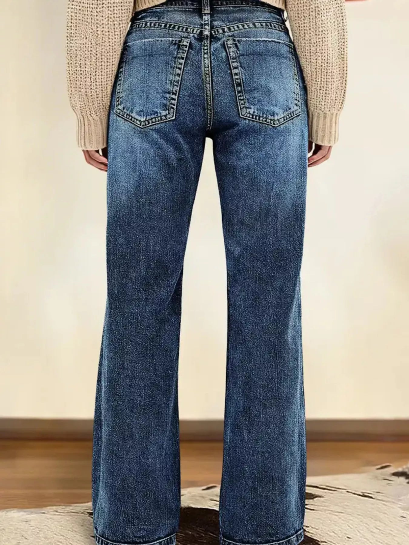 Person wearing blue flared jeans with a neutral background