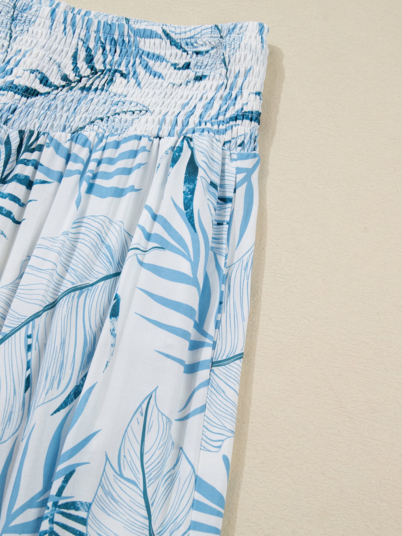 Blue leaf patterned pants on a beige background