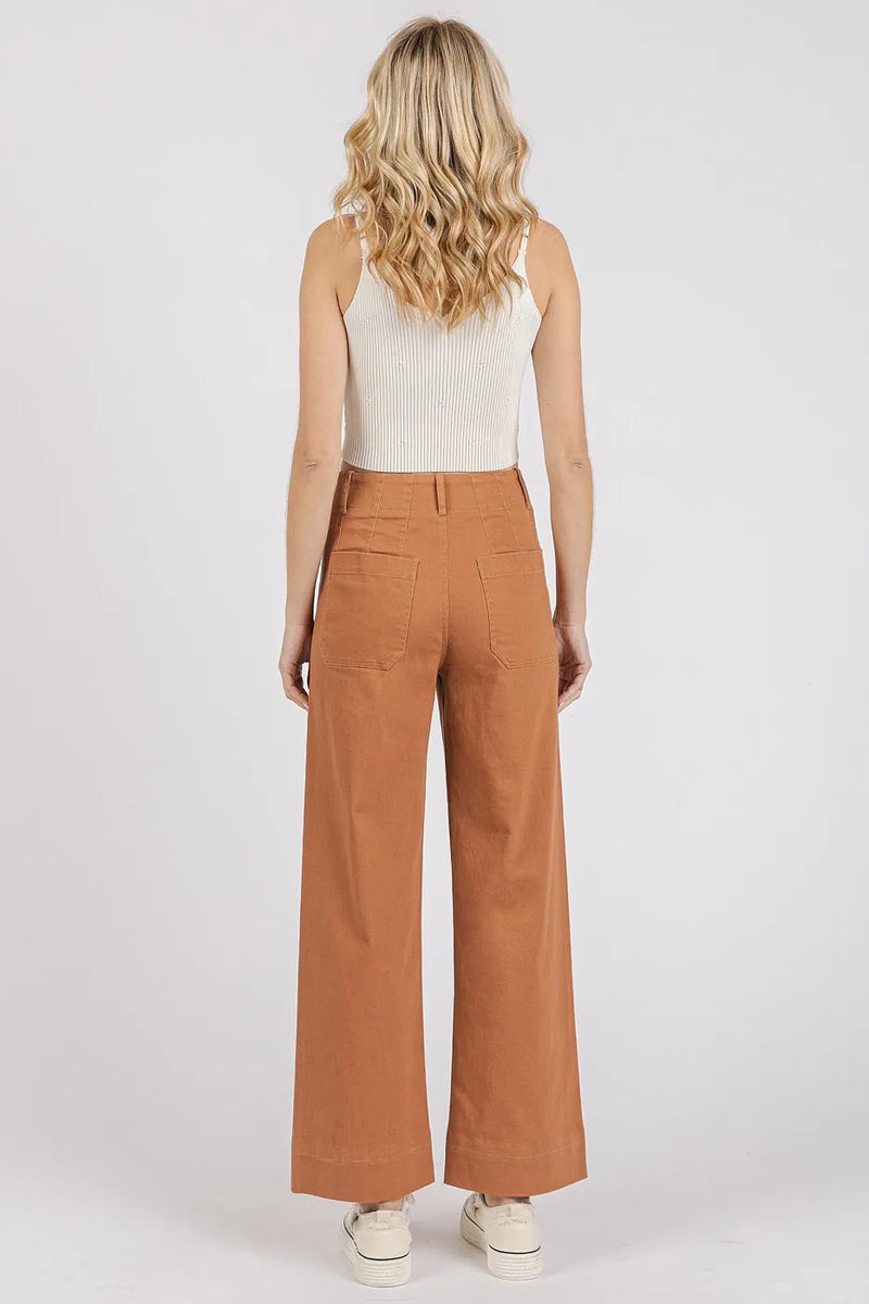 Woman wearing brown pants and a white top on a white background