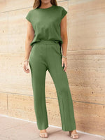 Woman wearing a green outfit standing against a beige wall.
