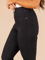 Black pants worn by a person on a beige background