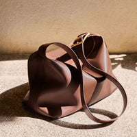 Brown leather handbag with a strap on a textured surface