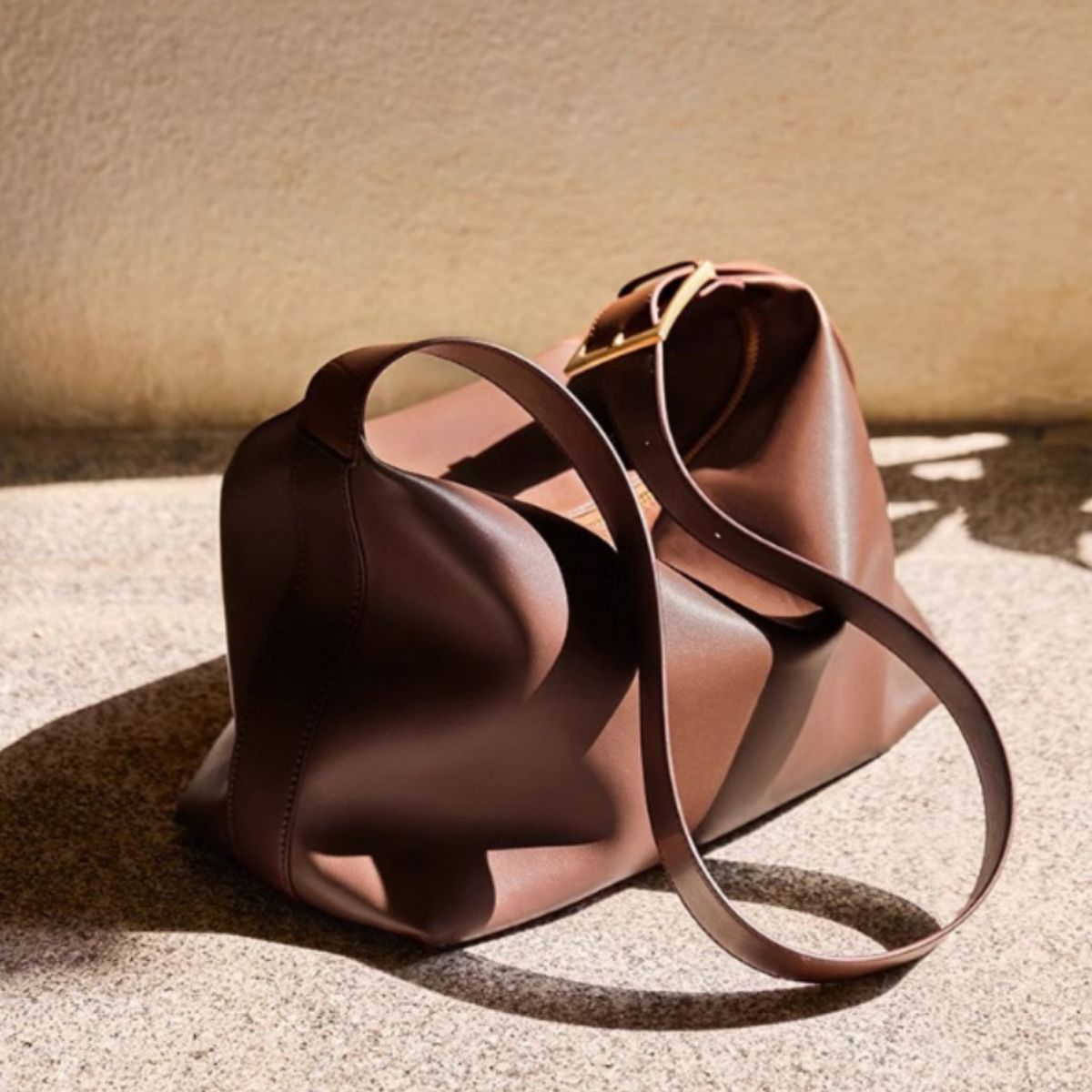 Brown leather handbag with a strap on a textured surface